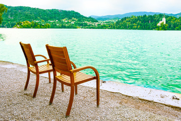 Two chairs on the shore of the resort lake. View of the mountains and the forest.