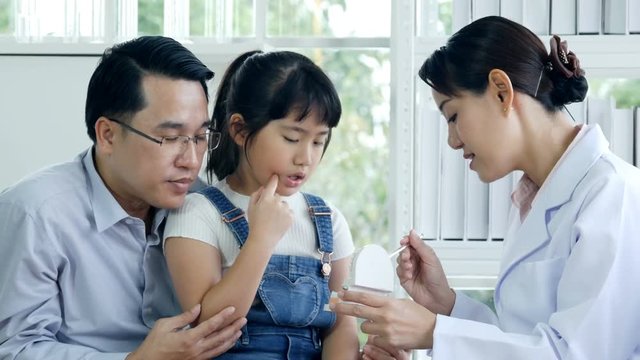 Little girl and father visiting to dentist and talking about problem. Doctor advising to her patient at dental clinic.