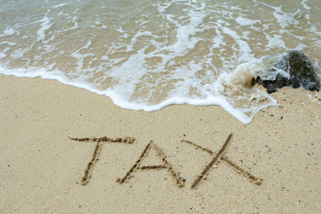 Tax text written on the sand beach, financial concept