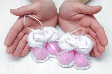 Newborn baby booties Christmas toy in father hands on white background.