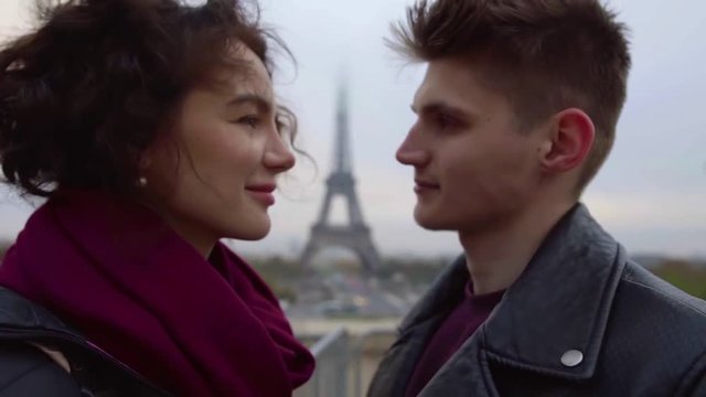 Close-up shot of a beautiful young couple staring into each others eyes outdoor smiling.