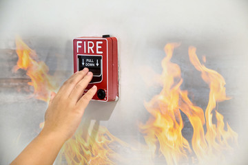Man is reaching his hand to push fire alarm hand station. Hand of man pulling fire alarm switch on...