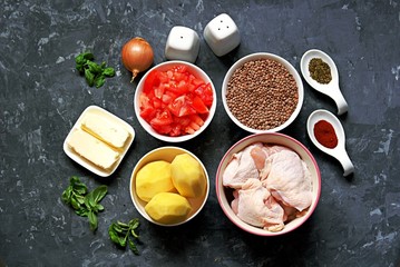 Ingredients for the preparation of chicken stew with lentils, potatoes and tomatoes: Chicken pieces, lentils, tomatoes, butter, peeled potatoes, onions, fresh basil, spices, salt, pepper. Top view.