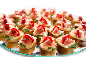 Close up of small canapes arranged on a plate over light background - selective focus