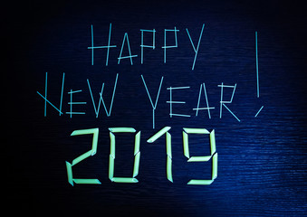 The inscription Happy new year 2019 on the blue wooden surface is made of pasta