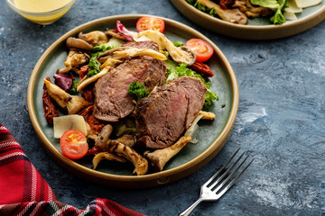 Salad with warm beef with oyster mushrooms, tomatoes and greens.