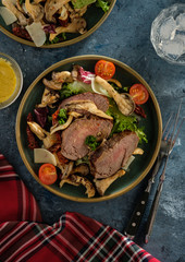 Salad with warm beef with oyster mushrooms, tomatoes and greens. Top view