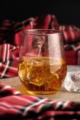 Still-life with a glass of bourbon. A glass of whiskey with ice. Concept of autumn spleen