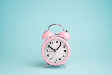 Pink alarm clock on blue background - obrazy, fototapety, plakaty