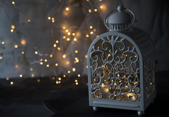 Candle in the lantern, Christmas tinsel, Christmas balls, sparkles and lights in the background. Night light Comfort in the house, Christmas decorations.