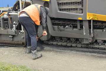road worker and paver in action
