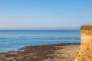 A Sussex coastal landscape with a sailing boat out at sea