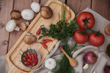 tomatoes in a clay plate, fresh greens, garlic and pepper in a ceramic plate