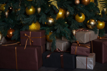 New Year's decor. Christmas tree, New Year, with brown and yellow balls. Brown and beige boxes with gifts are under the tree.