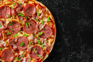Pepperoni Pizza with Mozzarella cheese, salami, bacon, Tomato sauce, pepper, Spices and Fresh green onion. Italian pizza on black background