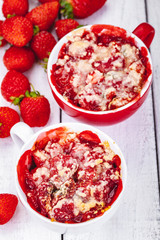 Strawberry crumble in cup on wooden rustic table. Close up