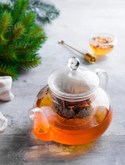 Glass teapot with flowers tied tea, Hot tea in glass teapot and honey with metal honey stick on stone background, Christmas concept