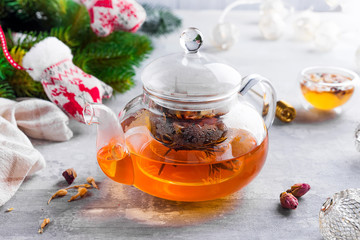 Glass teapot with flowers tied tea, Hot tea in glass teapot and honey with metal honey stick on stone background, Christmas concept
