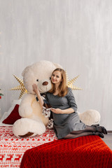 Very beautiful girl on the bed with a bear in the Christmas room.