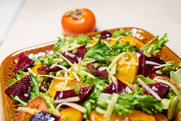 Healthy salad with lettuce salad, persimmon and beets. Persimmon salad. Diet. Vegetarian food.