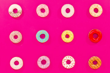 Texture of multicolored donuts on pink background. Sweets and food