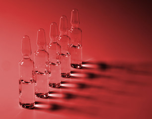 Row of ampulas with medicine on red background