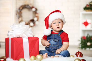 Baby boy with baubles and gift box sitting on floor at home