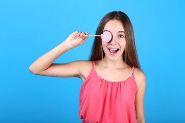 Young girl with lollipop on blue background