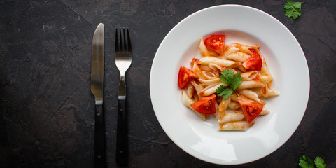 Penne Pasta with Tomato Sauce and Tomatoes. Vegan food.  (dark background). top view. copy space