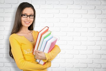 Young female student with books on  background