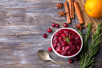 Homemade spicy cranberry sauce with fresh cranberries, cinnamon and star anise on a wooden background, free space © olepeshkina