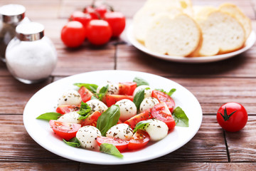 Mozzarella, tomatoes and basil leafs on brown wooden table