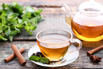 Cup of tea with mint leafs and cinnamon sticks on wooden table