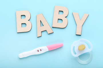Pregnancy test with pacifier on blue background