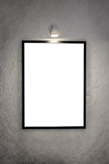 The picture in a black frame, hanging on the wall and illuminated by a lamp for paintings. On the background of a white wall, decorative structural plaster with glitter. Mock up.