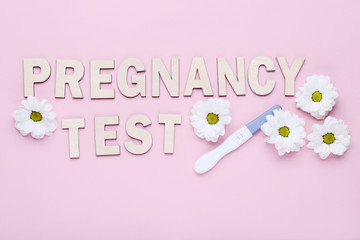Pregnancy test with chrysanthemum flowers on pink background