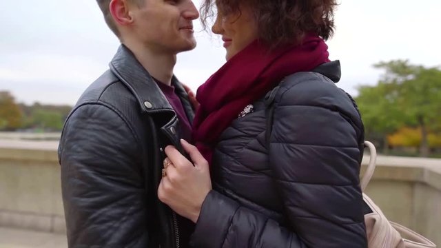 Close-up shot of a hugging young couple outdoor in autumn, smiling happy faces.