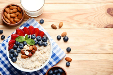 Oatmeal with berries and nuts in bowl on wooden table