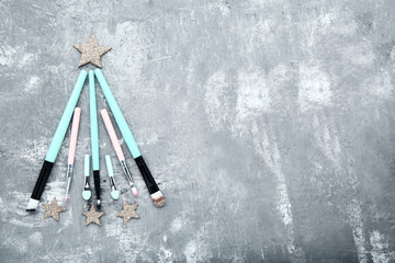 Makeup brushes in shape of christmas tree on grey wooden table