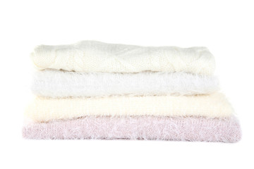 Stack of folded sweaters on white background