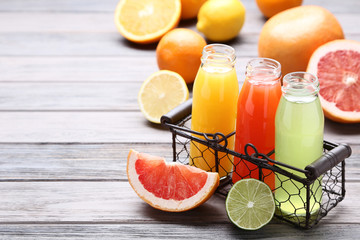 Citrus juice in glass bottles with fruits on wooden table