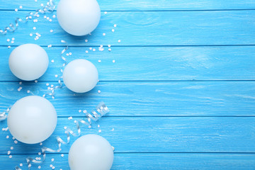 White balloons with confetti on blue wooden table