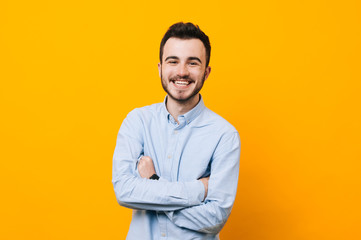 Portrait of handsome young guy standing against yellow wall.