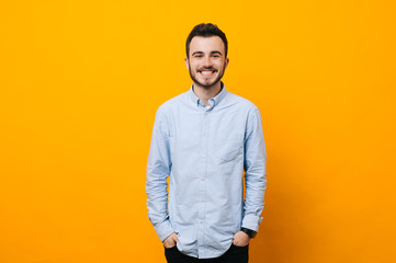 Handsome young man on yellow background looking at camera. Portrait of laughing young man with...