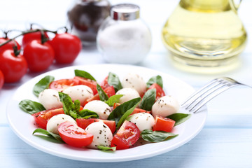 Mozzarella, tomatoes and basil leafs on wooden table