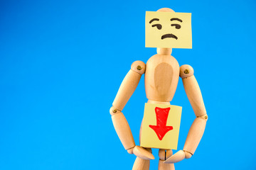 Abstract image of wooden dummy with sticker on its face has pain in genitals on blue background. Concept of health issues.