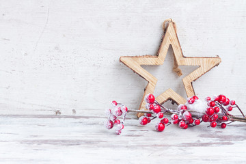 red and white christmas - twig with berries and star on aged wooden background