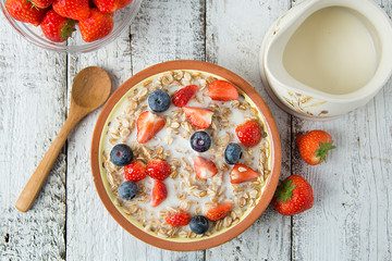 Healthy Homemade Oatmeal with Berries - fresh strwberries and blueberries, for Breakfast. Rustic white wooden table.