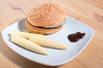 hamburger with mini corn on a plate. Horizontal photo format
