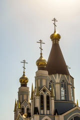 Fototapeta na wymiar Russian Orthodox Church towers with three domes and crosses at sunlight